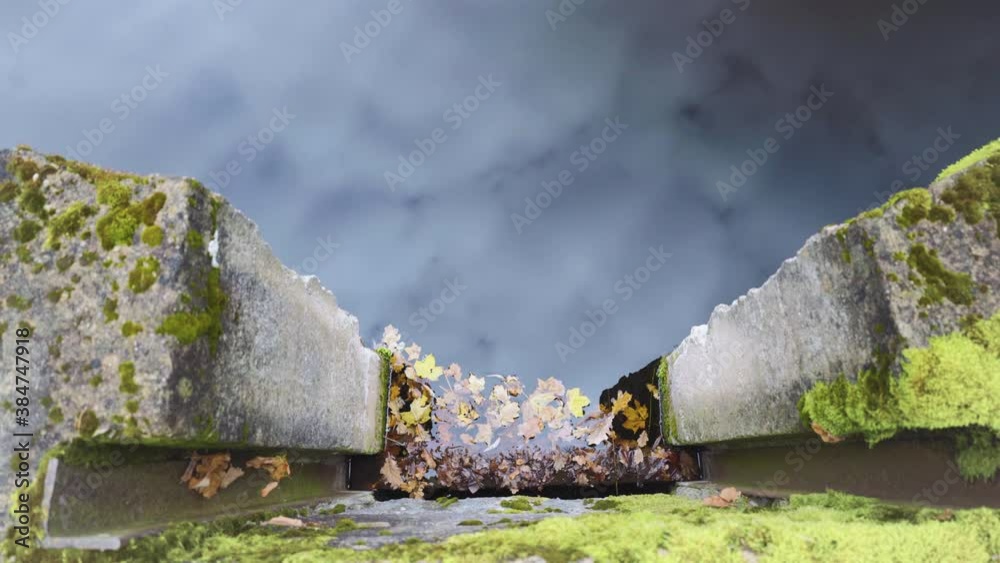Autumn scene. Fallen leaves in the river, a fragment of a wooden bridge. The sky are reflected in the water. Concrete fencing with green moss of the dam on the shore. Autumn scene. Fallen leaves in the river, a fragment of a wooden bridge. The sky are reflected in the water. Concrete fencing with green moss of the dam on the shore.