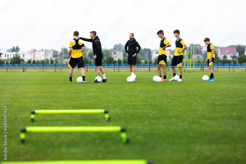 Soccer Team on Training. Group of Young Football Players With Coaches on Grass Practice Field. Young Coach Explaining Training Game Plan to Team Soccer Team on Training. Group of Young Football Players With Coaches on Grass Practice Field. Young Coach Explaining Training Game Plan to Team