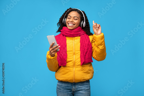 Black Woman In Headphones Listening Music On Smartphone, Blue Background
