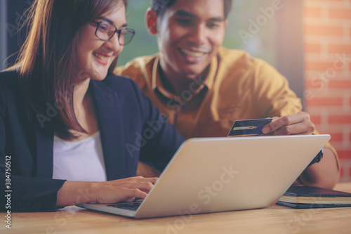 Wallpaper Mural Asian young couple shopping online while sitting at workplace with credit card and laptop computer. Selected focus Torontodigital.ca