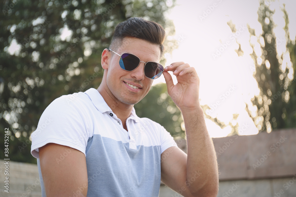 Handsome man wearing stylish sunglasses on city street