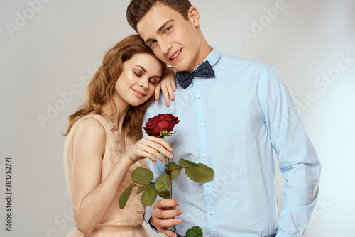 A loving young couple with a red rose in their hands on a light background romance