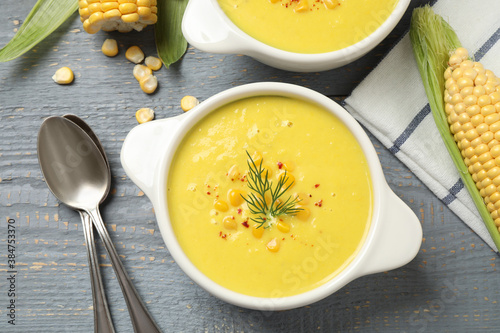 Delicious creamy corn soup served on grey wooden table, flat lay