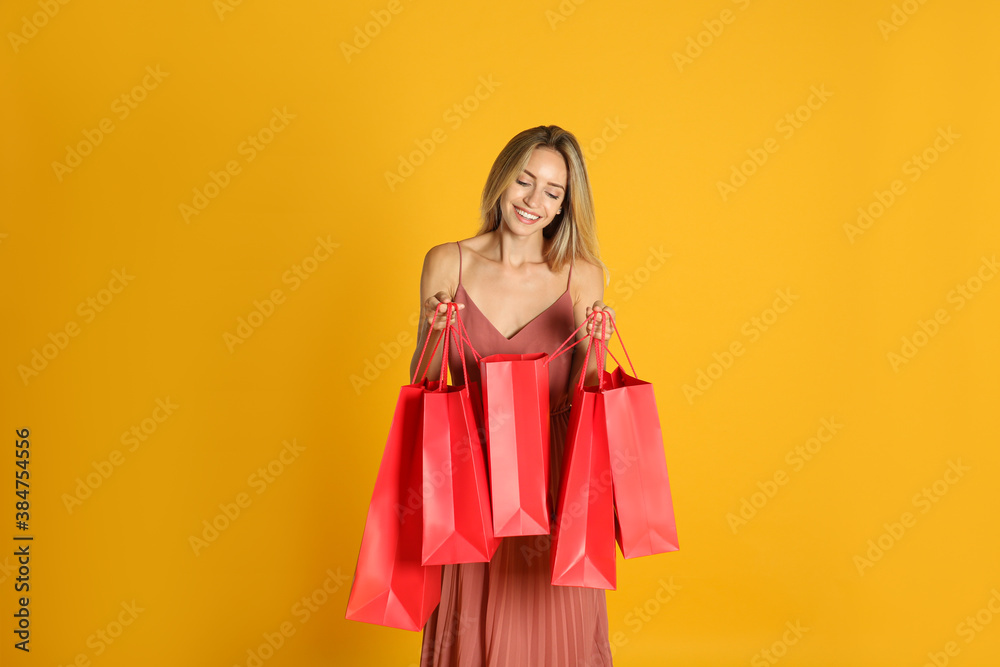 Happy young woman with shopping bags on yellow background. Black Friday Sale