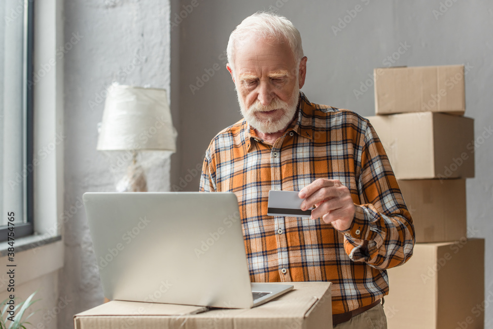 senior man making online purchase with credit card and laptop senior man making online purchase with credit card and laptop