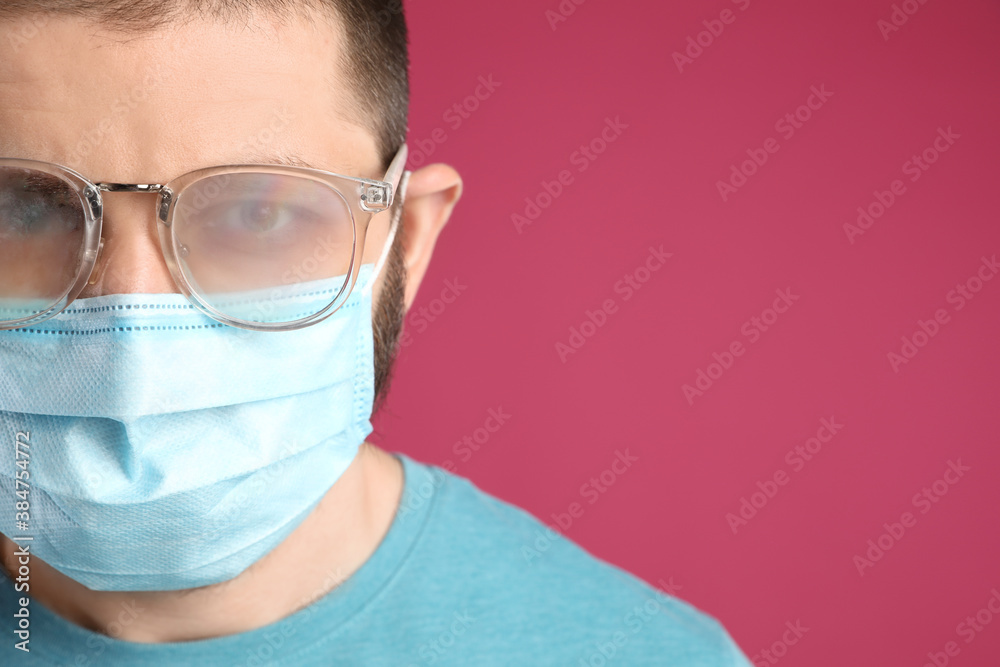 Man with foggy glasses caused by wearing disposable mask on pink background, space for text. Protective measure during coronavirus pandemic Man with foggy glasses caused by wearing disposable mask on pink background, space for text. Protective measure during coronavirus pandemic