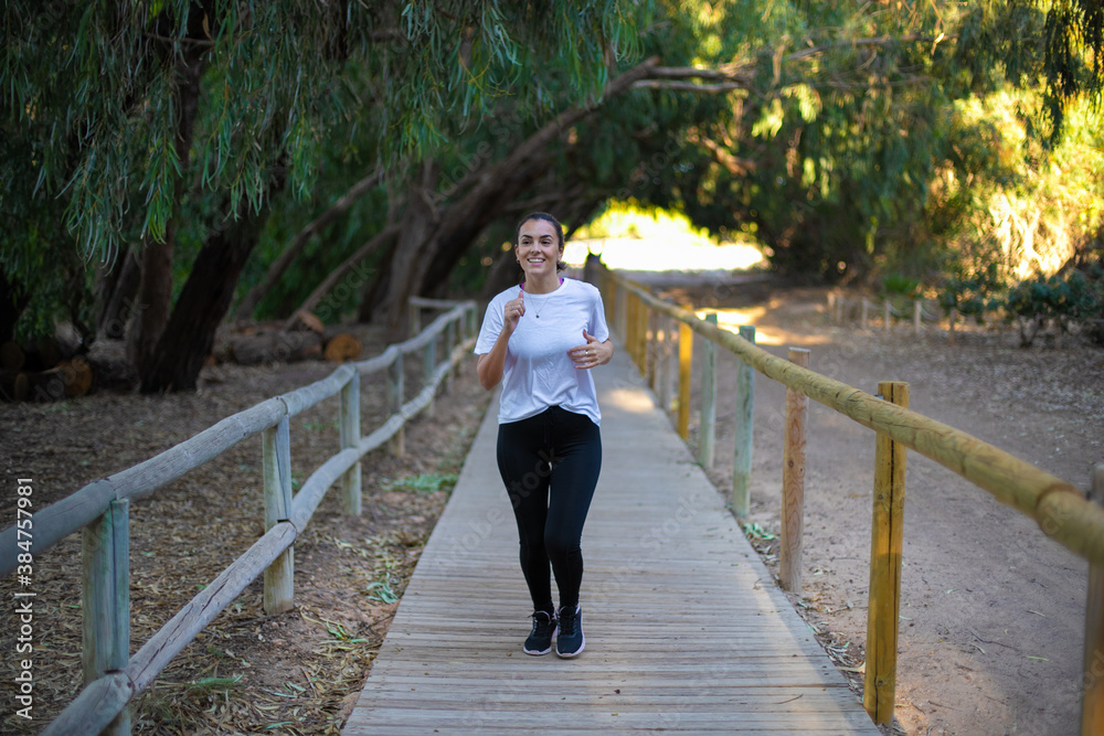 Young beautiful woman practicing sport in the forest very happy and smiling Young beautiful woman practicing sport in the forest very happy and smiling