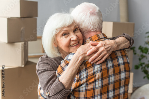 senior woman hugging husband in new house, moving concept