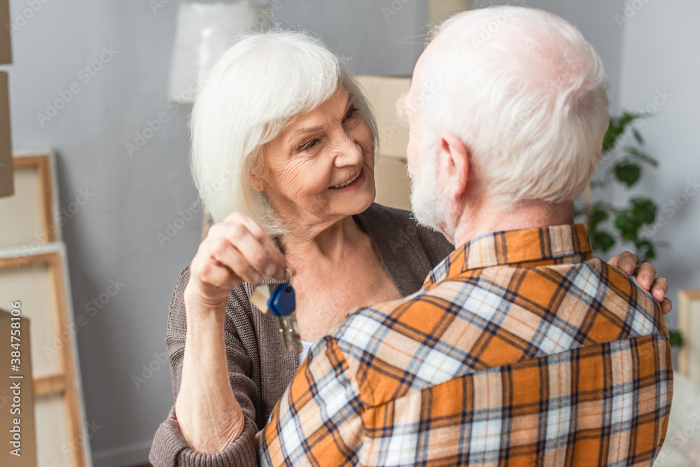 senior woman holding keys and hugging husband, moving concept senior woman holding keys and hugging husband, moving concept