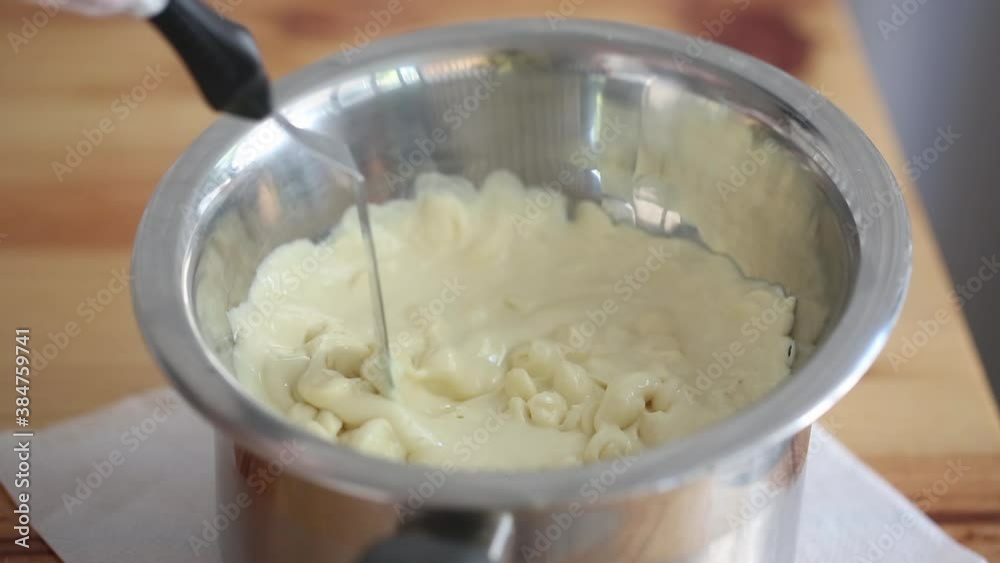 Сhef mixing melting white chocolate in a cup Сhef mixing melting white chocolate in a cup