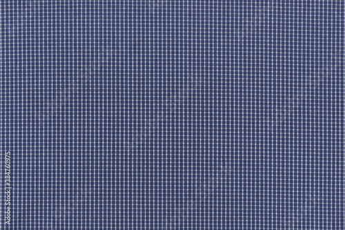The texture of natural cotton fabric is a small blue and white check. Abstract background of a traditional classic cowboy-like fabric.