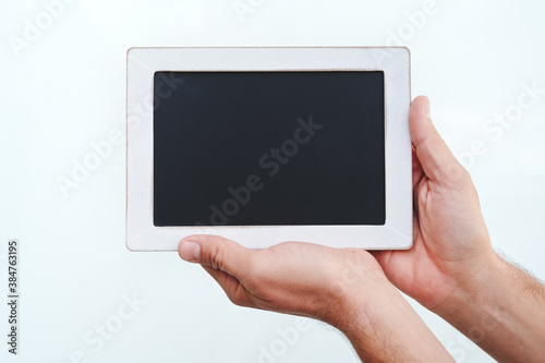 man's hands holding chalkboard on white background