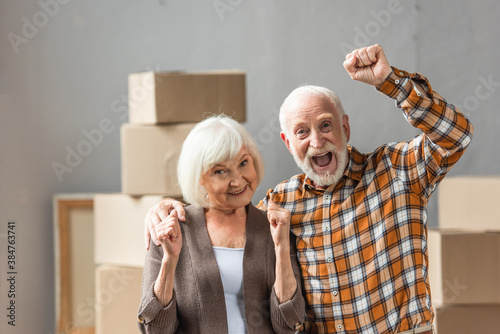 excited senior couple with fists up showing hooray sign, moving concept photo