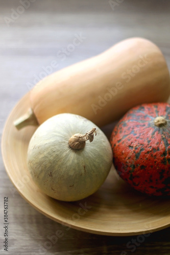 Wooden bowl with three different pumpkins. Selective focus.