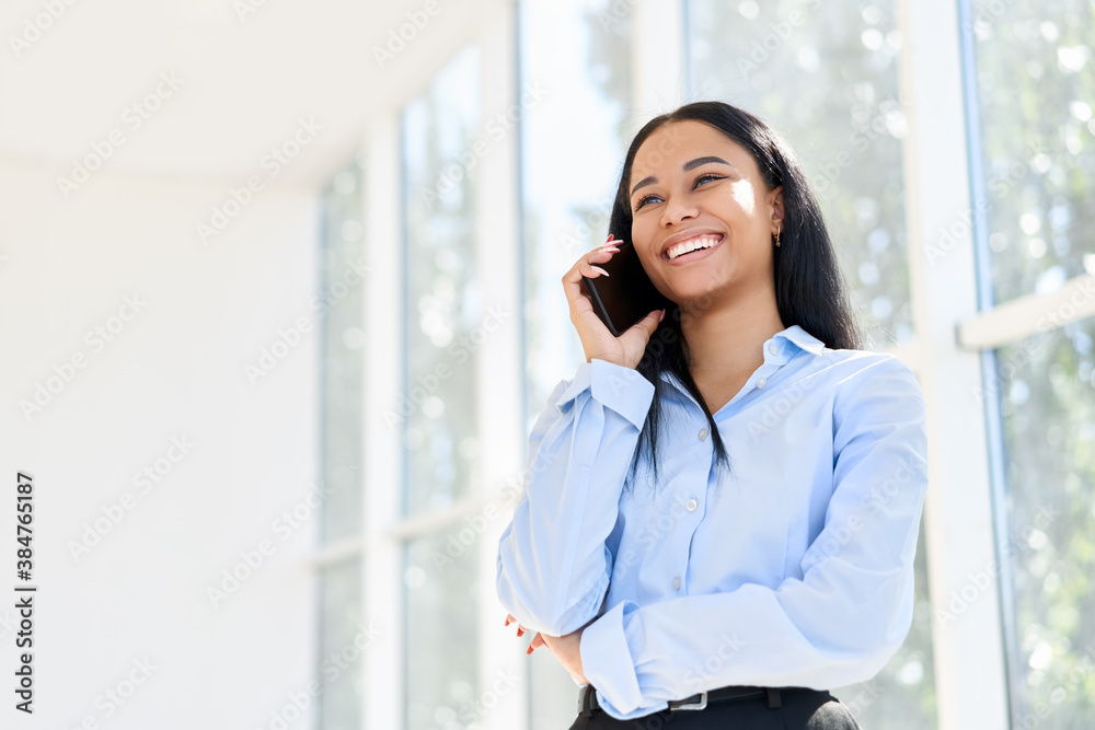 Smiling African American businesswoman talking on phone in open space modern office Smiling African American businesswoman talking on phone in open space modern office