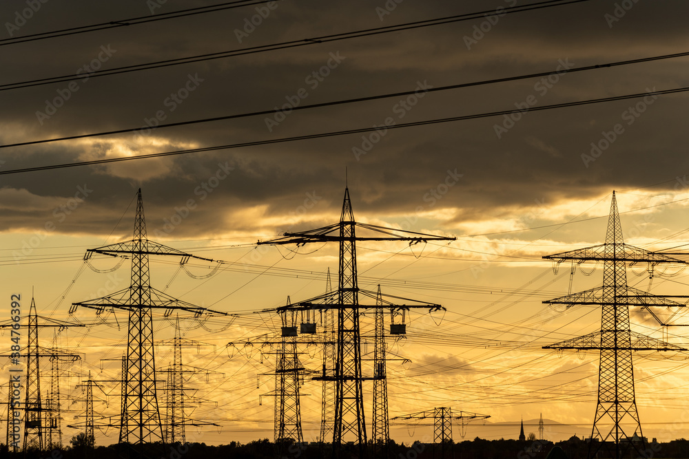 Hochspannungsmasten als Silhouetten in der Abenddämmerung , Energieverbindung vom Kraftwerk zum Verbraucher.