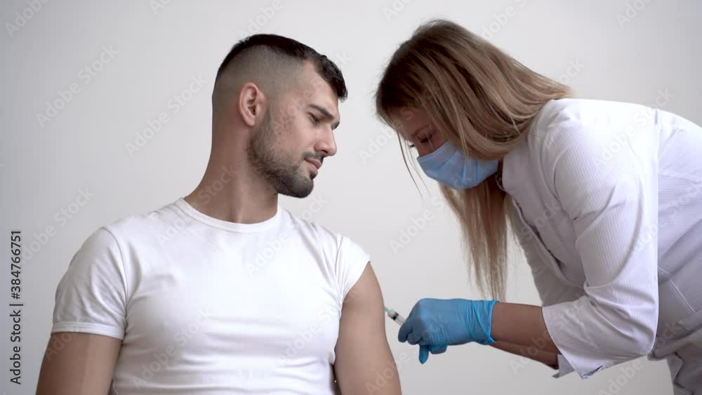 COVID‑19 vaccine. Female doctor giving injection to a male patient. COVID‑19 vaccine. Female doctor giving injection to a male patient.