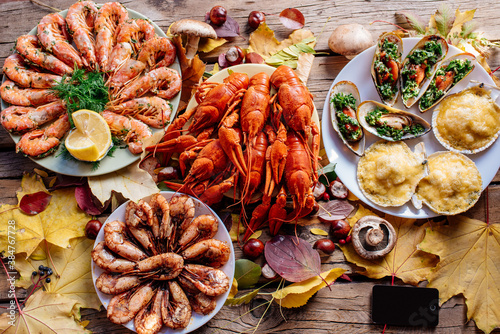 Fotografie Shrimps, mussels, crayfish and scallops on wooden table