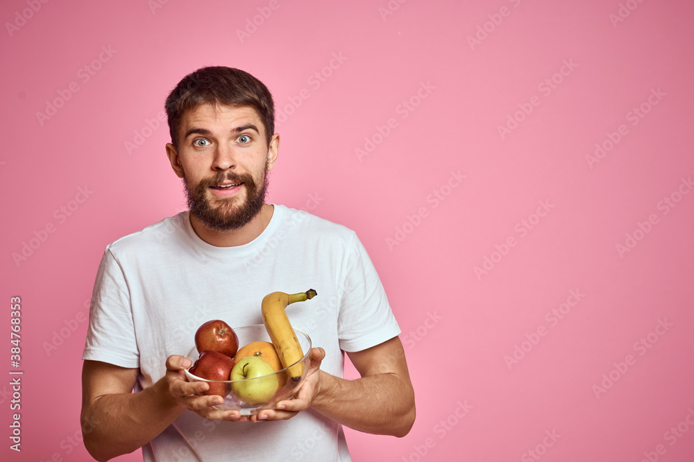 energetic man with fresh fruit in a cup on a pink background copy space energetic man with fresh fruit in a cup on a pink background copy space