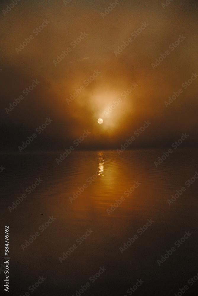 Amanecer entre la bruma, con el Sol reflejado en el agua