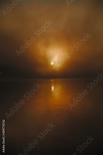 Amanecer entre la bruma, con el Sol reflejado en el agua