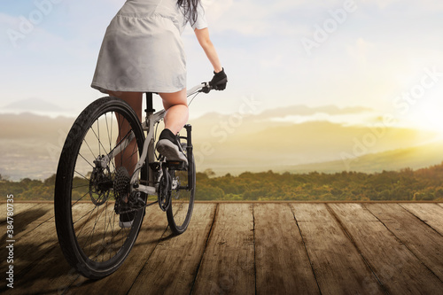 Rear view of a woman riding a bicycle on a wooden path