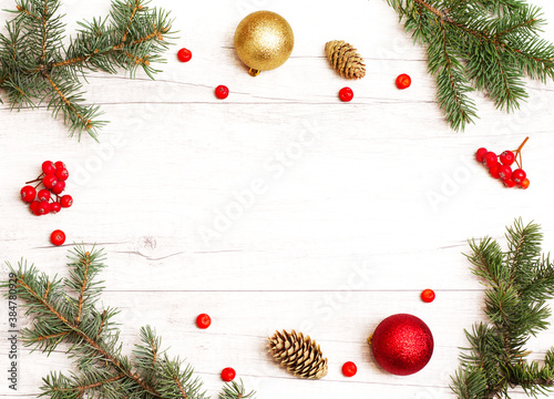 Merry Christmas frame and wallpaper. Happy New Year composition. Christmas balls, red berries, pine cones, fir branches on wooden white background