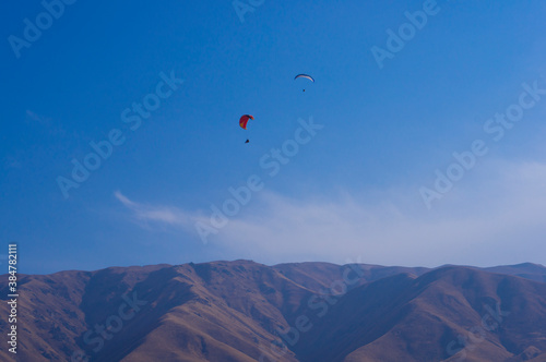 Paragliding. A man flies on a parachute against the blue sky.