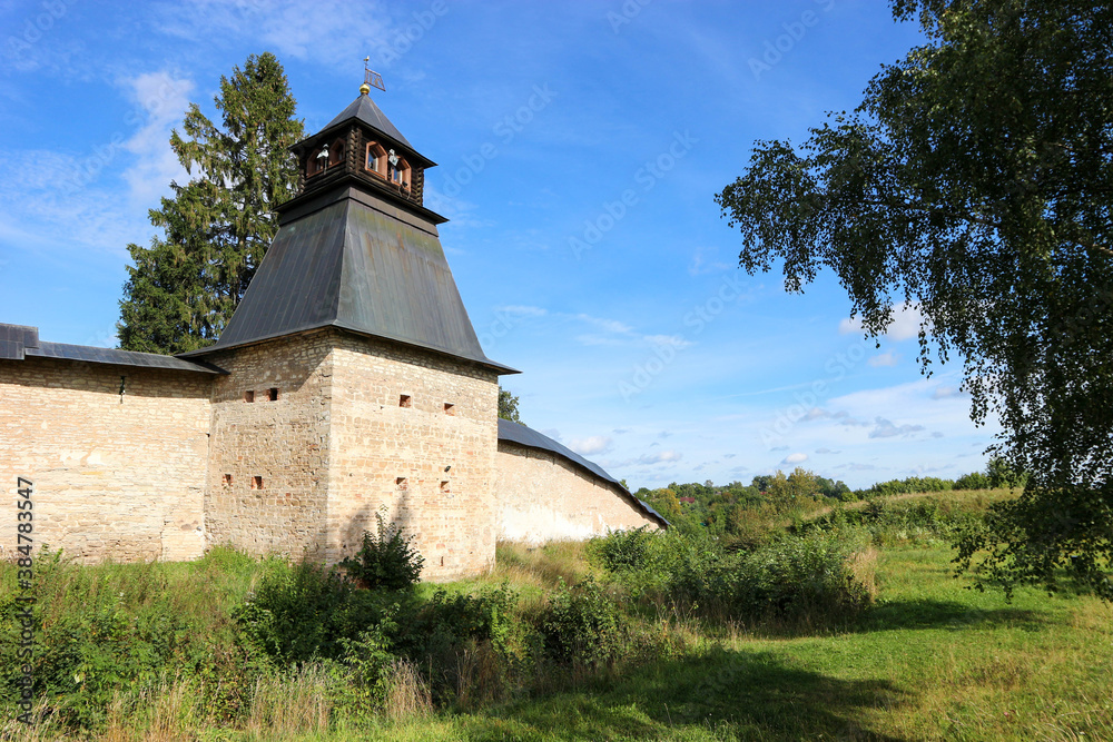 Fortress wall and tower of Pskov-Pechory Dormition Monastery in Pechory, Pskov region, Russia under blue sky