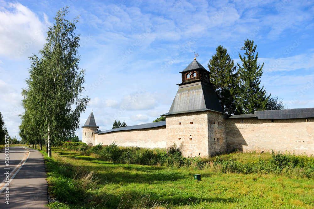 Fototapeta premium Beautiful summer panoramic view to the fortress wall and tower of Pskov-Pechory Dormition Monastery in Pechory, Pskov region, Russia under blue sky