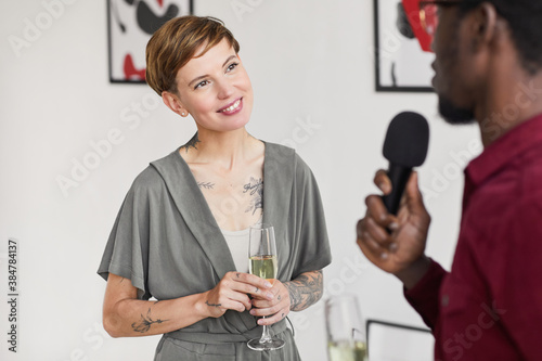 Waist up portrait of tattooed elegant woman giving interview while opening modern art gallery exhibition, copy space photo