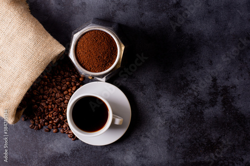 TOP VIEW OF A Hessian BAG WITH COFFEE BEANS, A COFFEE MAKER AND A FULL CUP OF COFFEE