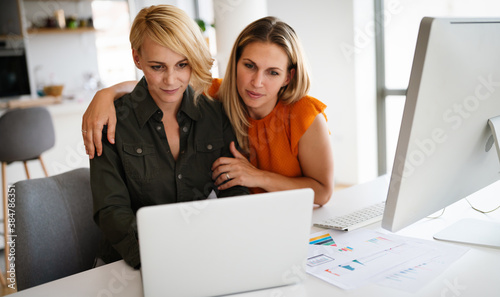 Happy lesbian couple planning, brainstorming at startup in office