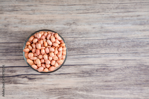 Peanuts in a bowl wood table. The peanut also known as the groundnut  or goober or monkey nut is a legume crop grown mainly for its edible seeds.