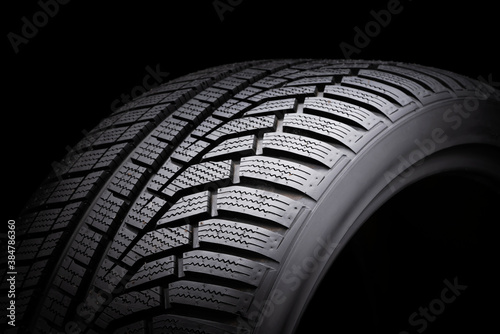 winter tire, driving safety on snowy and icy roads. asymmetric tread pattern. close-up on a black background © Vladimir Razgulyaev