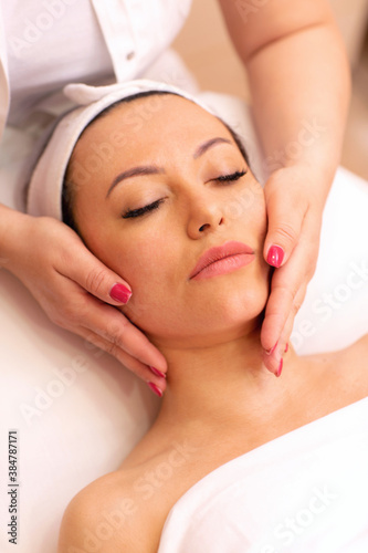 Experienced masseuse hands massaging a face of a woman