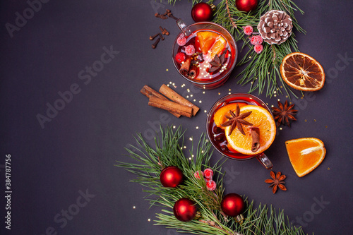Two cups of mulled wine and Christmas decor on a black background. Flat lay style