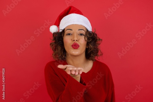 Cute appealing female blows kiss at camera, demonstrates love to boyfriend or says goodbye on distance, isolated over white studio background. Attractive young woman shows sympathy to someone.