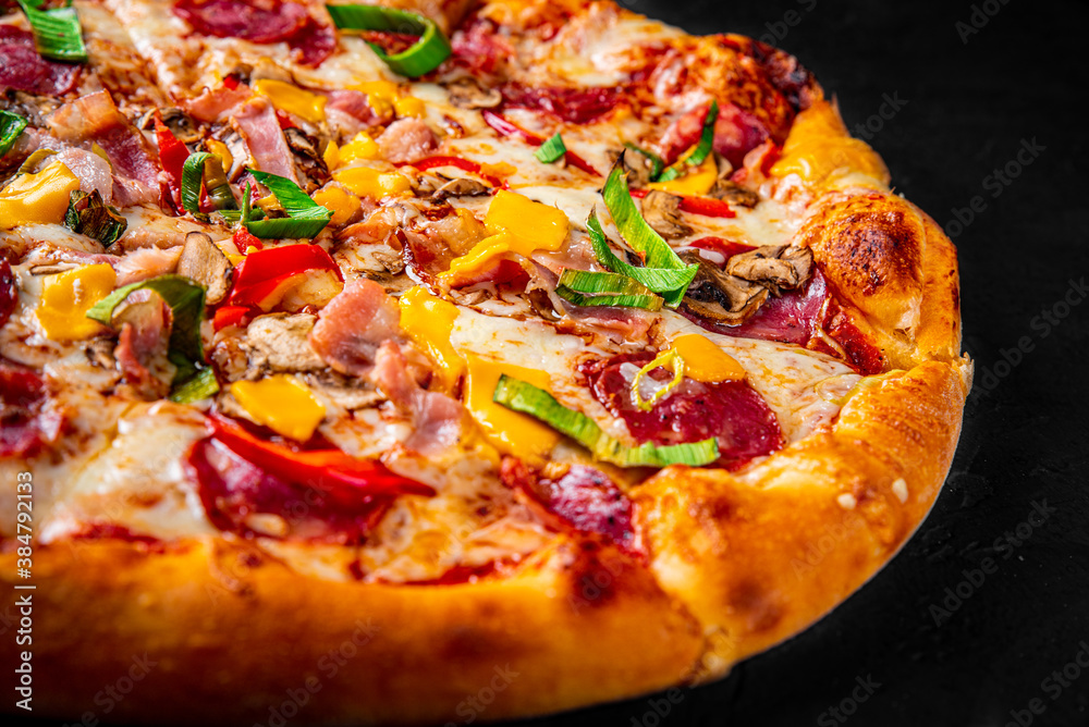 Pizza with Mozzarella cheese, salami, chicken meat, beef, ham, Tomato sauce, pepper, spices. Italian pizza on Dark grey black slate background Pizza with Mozzarella cheese, salami, chicken meat, beef, ham, Tomato sauce, pepper, spices. Italian pizza on Dark grey black slate background