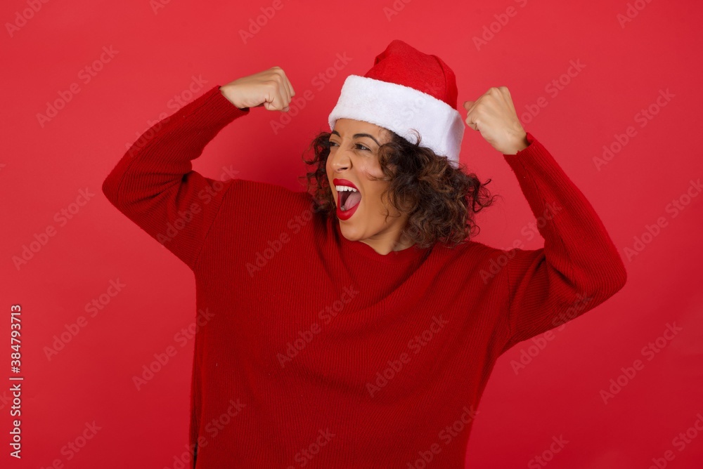 Yes I am winner. Portrait of charming delighted and excited caucasian woman wearing Christmas hat raising up fist in triumph and victory smiling achieving success grinning from delight. Yes I am winner. Portrait of charming delighted and excited caucasian woman wearing Christmas hat raising up fist in triumph and victory smiling achieving success grinning from delight.