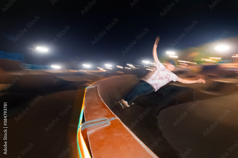 Motion in blur young skater is rolling down the ramp at night in a ...