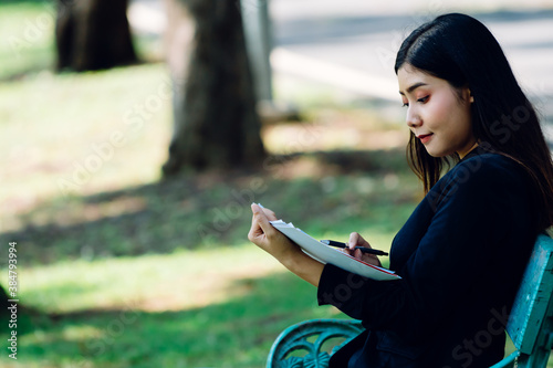 Asian women with long hair in work clothes Happily reading business papers in the park