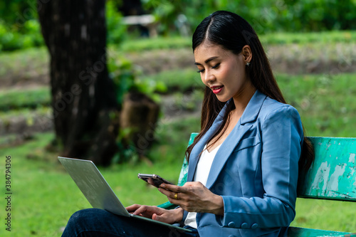 Thai Business Woman typing on Laptop keyboard to working in public park