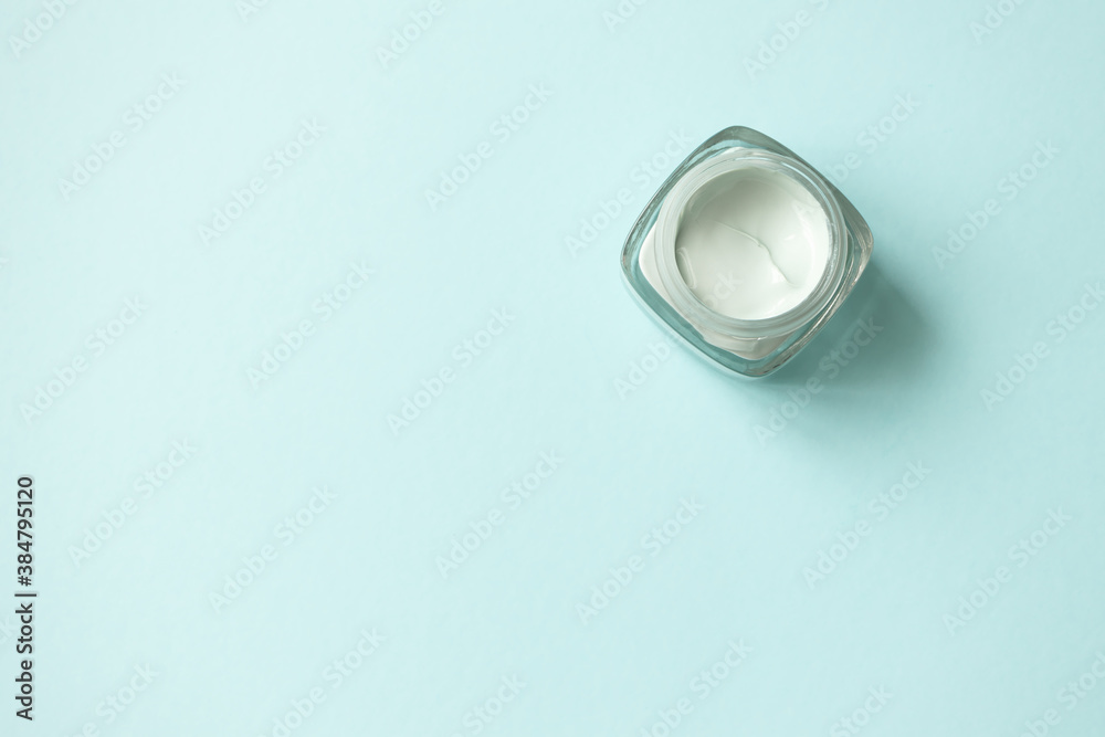 Facial green clay mask on light blue background with copy space, top view. Skin care beauty antibacterial sooting detox product minimalistic flat lay