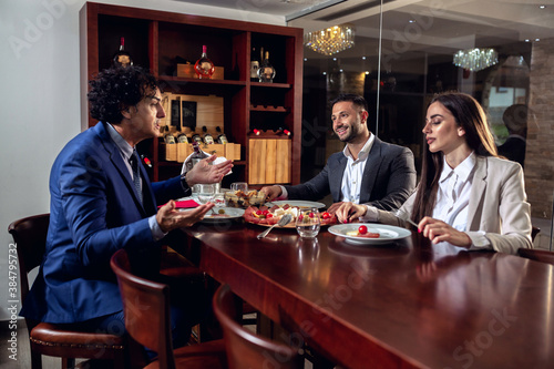 Three elegantly dressed business people having dinner