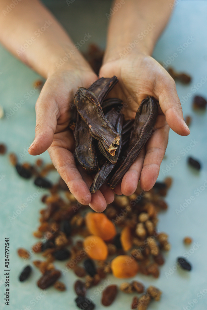 a handful of carob, on green background