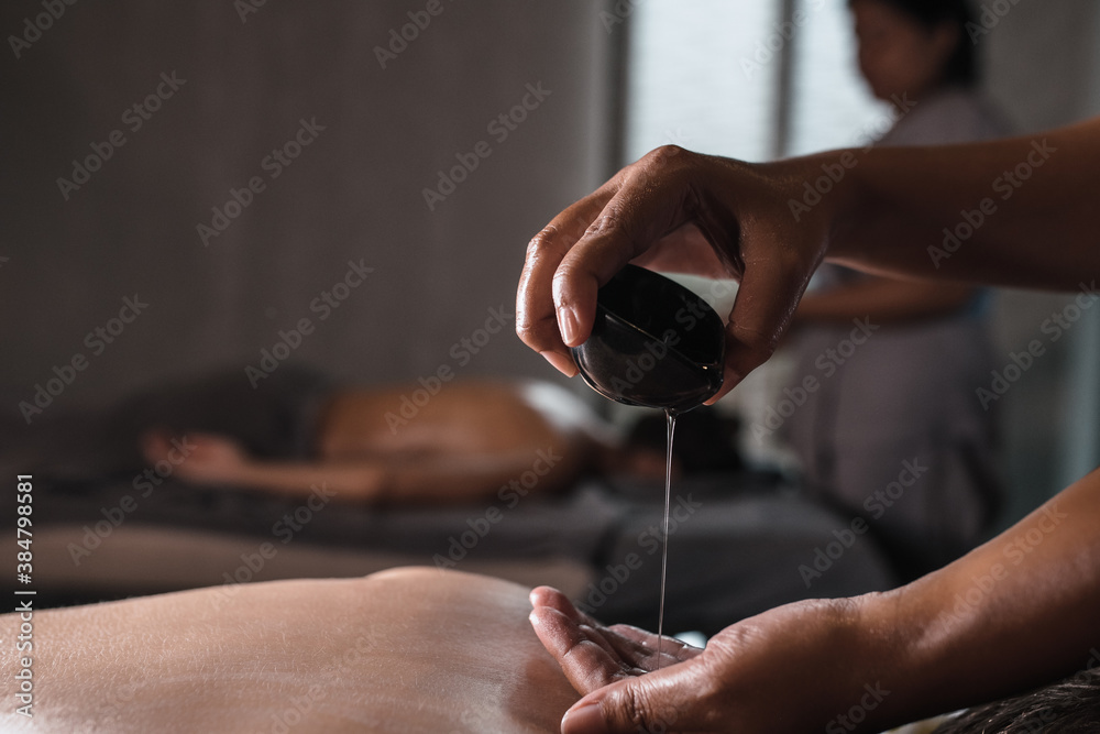 Fotografia do Stock: Closeup of masseur hands pouring aroma oil on woman  back. Masseuse prepare to do oriental spa procedure for relaxing treatment.  Therapist doing aromatherapy oil massage on woman body.