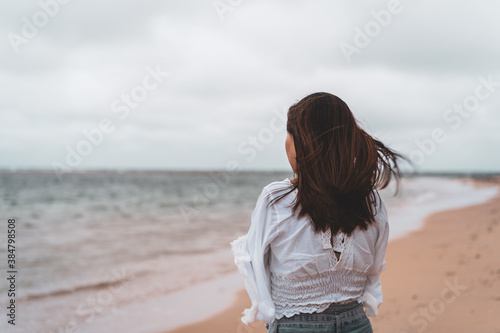 Young woman feeling lonely and sad looking at the sea on a cloudy day