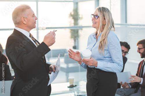 businessman and businesswoman talking standing in the office.