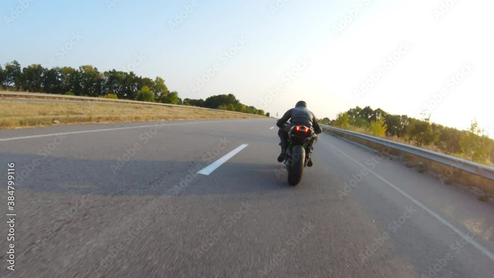 Aerial shot of man riding fast on modern sport motorbike at highway during sunset. Motorcyclist racing his motorcycle on country road. Guy driving bike during trip. Concept of freedom and adventure Aerial shot of man riding fast on modern sport motorbike at highway during sunset. Motorcyclist racing his motorcycle on country road. Guy driving bike during trip. Concept of freedom and adventure